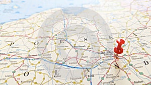 A red pin stuck into Warsaw on a map of Poland