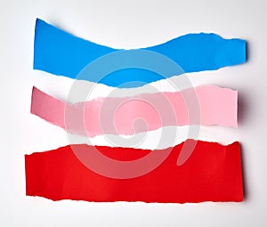 red, pink and blue torn strips of paper on a white background