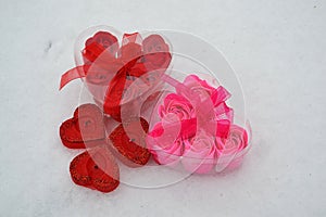 Red and pink heart in the melted snow. three red candles in the shape of a heart.