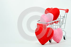 Red and Pink hearts in mini shopping cart falling on the background for valentines day. Top view and copy space