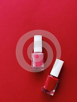 Red and pink nail polish bottles on red background, manicure and beauty cosmetics