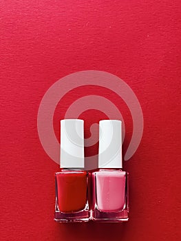 Red and pink nail polish bottles on red background, manicure and beauty cosmetics