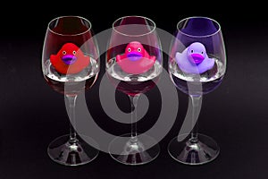 Red, pink and purple rubber ducks in wineglasses