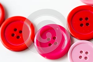 Red and pink sewing buttons on white background