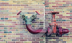 Red pipe line with brown valve on colorful brick wall