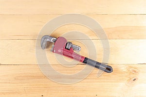 Red pipe wrench with a wooden background