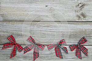 Red plaid Christmas bows border rustic wooden background