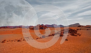 Red planet with arid landscape, rocky hills and mountains, and a giant Mars-like moon at the horizon