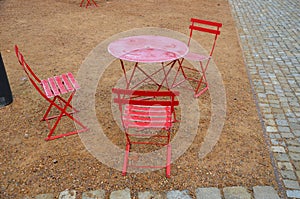 Red plastic benches in the shape of blocks with handles. The square is paved with granite cubes. sandy surface. built around a squ