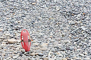 Red plastic buoyancy aid in the sand on lonely beach.