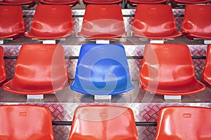 Red plastic chairs with blue seats in the middle.Concept the courage to be different.