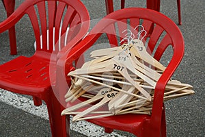 Red plastic chairs with empty wooden hangers for clothes.