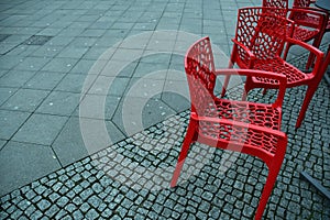Red plastic chairs at streetside cafe