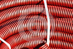 Red plastic corrugated hose for insulation and laying of wires and cable close-up.