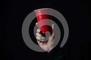 Red plastic cup with a hand in the dark.
