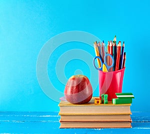 red plastic cup with multi-colored wooden pencils stands on a stack of books