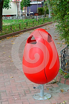 Red plastic garbage can in the park
