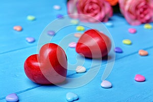 Red plastic hearts and roses on wooden background