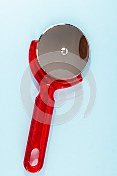 A red plastic pizza cutter with a silver handle