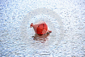 Red plastic river buoy on the calm water surface