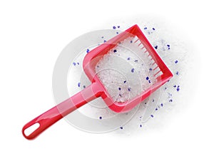 Red plastic scoop with cat litter on white, top view