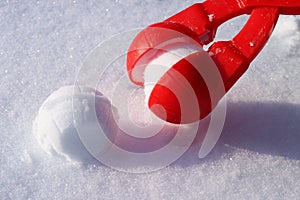 red plastic snowball maker on the white snow. The concept of winter holidays