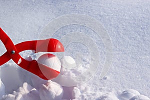 red plastic snowball maker on the white snow. The concept of winter holidays