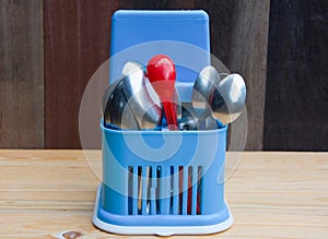 Red plastic spoon and stainless spoons in blue plastic storage