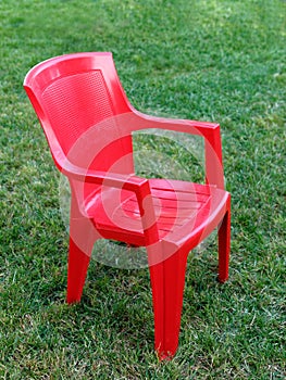 Red plastic vacant chair grass