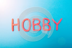 Red plasticine hobby lettering on blue background, hobbies concept, inscription