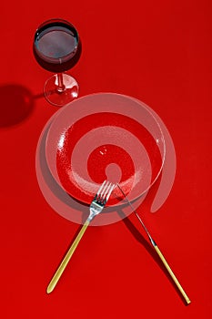 Red plate, knife and fork on a red table. Top view. Copy space