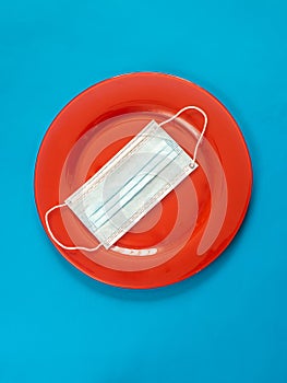 Red plate with mask on blue - Cooking and eating in p