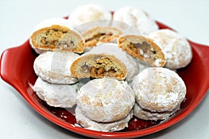 Red plate of traditional Arabic cookies for celebration of Islamic holidays of El-Fitr feast, Egyptian Kahk covered with sugar