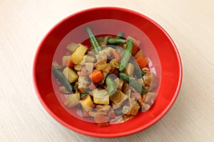 Red plate with vegetable stew