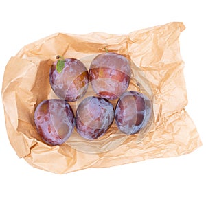 Red plums, fruit, on ecologically sound brown paper bag, isolated on white background. photo