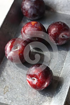 Red plums in a grey tray