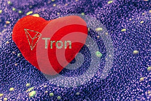 The cryptocurrency Tron symbol is a red plush heart with a neon background. TRX