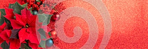 Red poinsettia flower and festive Christmas arrangement on red background. Top view, copy space. Xmas banner