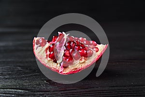 Red pomegranate on a black wooden background, food shot