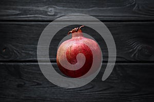 Red pomegranate on a black wooden background, food shot