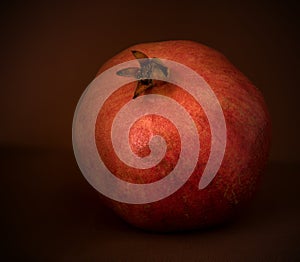 Red pomegranate lies on a brown background, still life with fruit, harvest