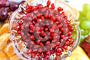 Red pomegranate seeds in a bowl with fresh fruits