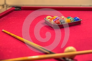 Red pool table with billiard balls in the rack