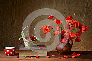 Red poppies in a ceramic vase, books,cherries and metal pots on the table