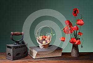 Red poppies in a ceramic vase, books, cherries and old flatiron