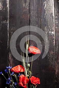 Red poppy, cornflowers and rye on old wood with scratches