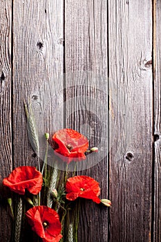 Red poppy flower and rye on old wood