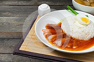 Red pork rice with sweet sauce and boiled egg in white on wooden table