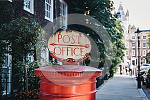 Red post box with a retro Post Office sign in London, UK.