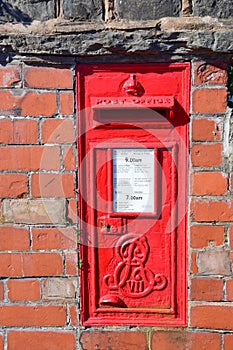 Red postbox mounted in a brick wall